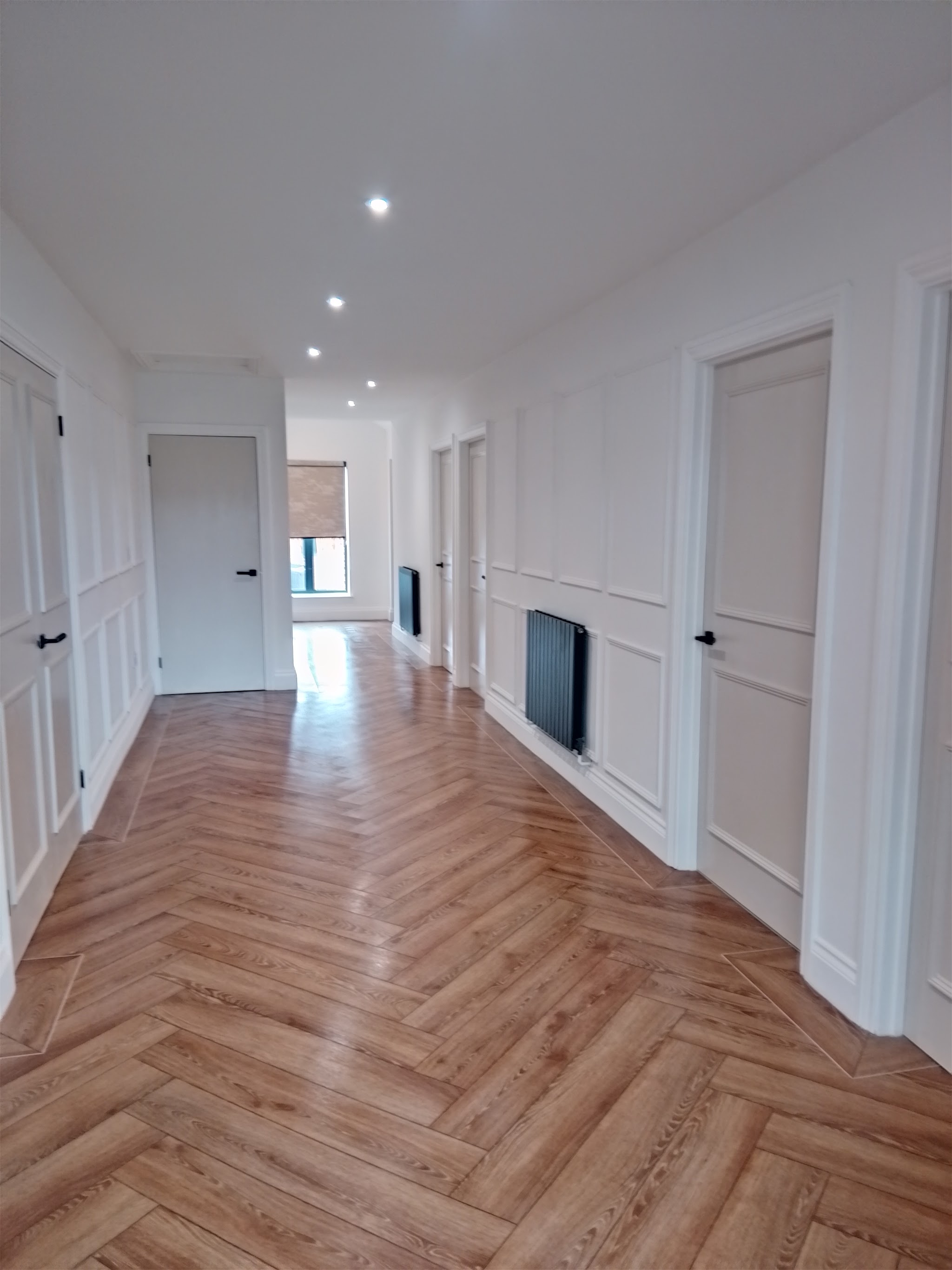 Long white panelled hallway with herringbone flooring, freshly decorated
